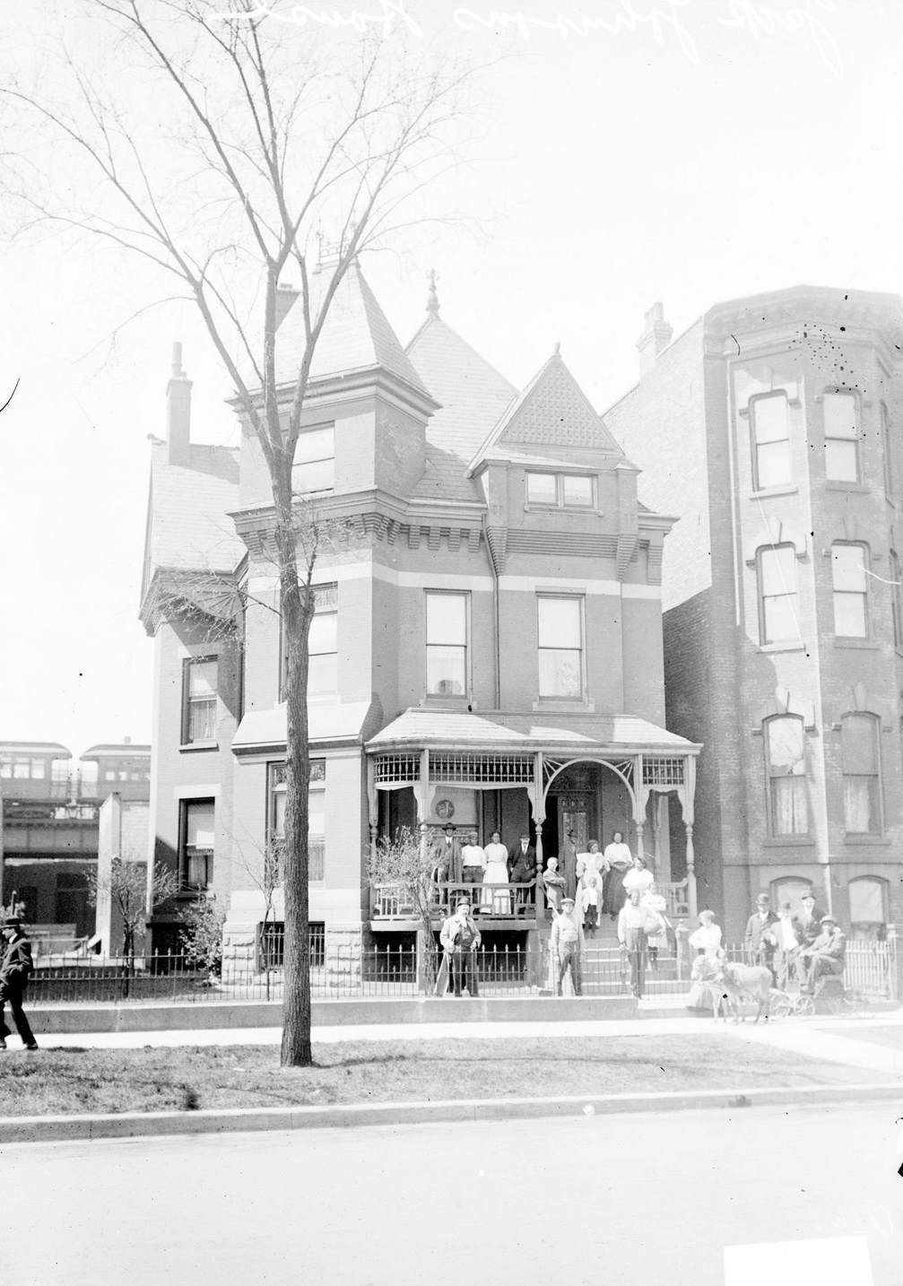 The home of Jack Johnson in Chicago, IL, 1910. Many people are standing on the porch and in front of the building.