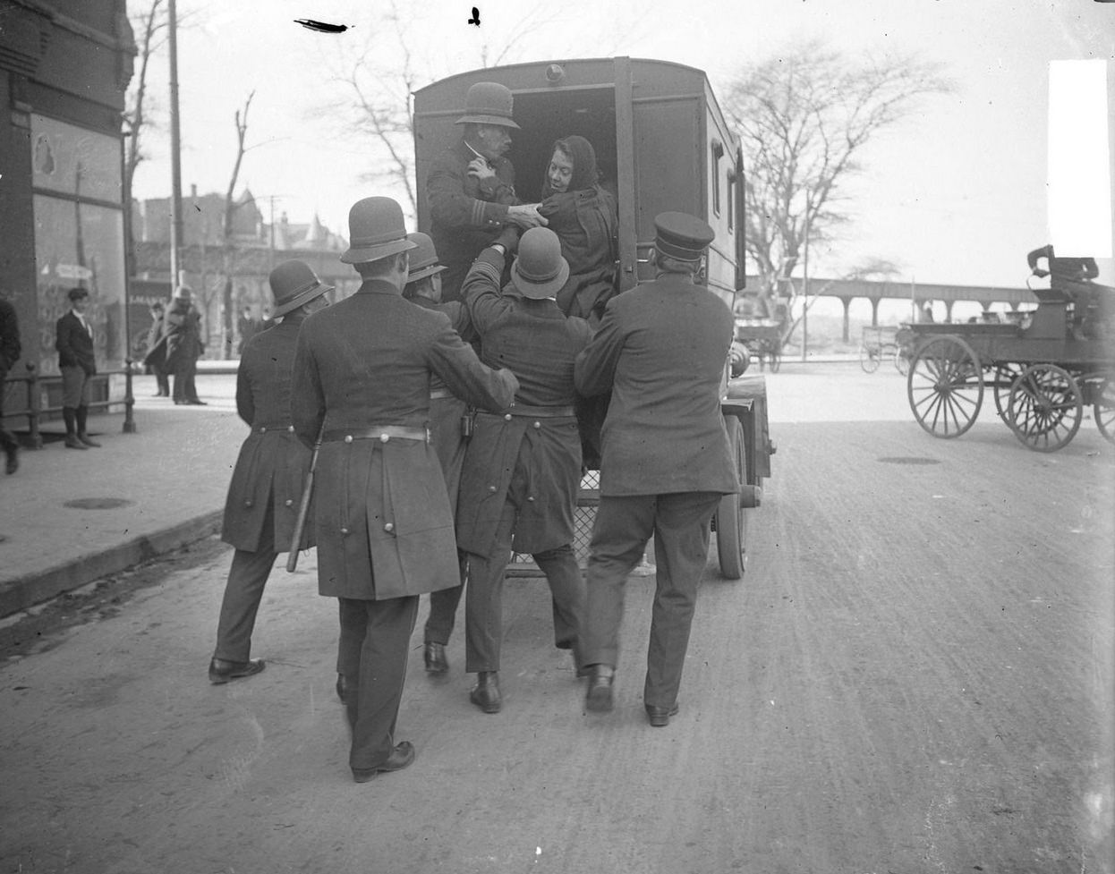 Police putting a woman into the back of a police wagon during Garment Workers Strike, Chicago, Illinois, 1910s.