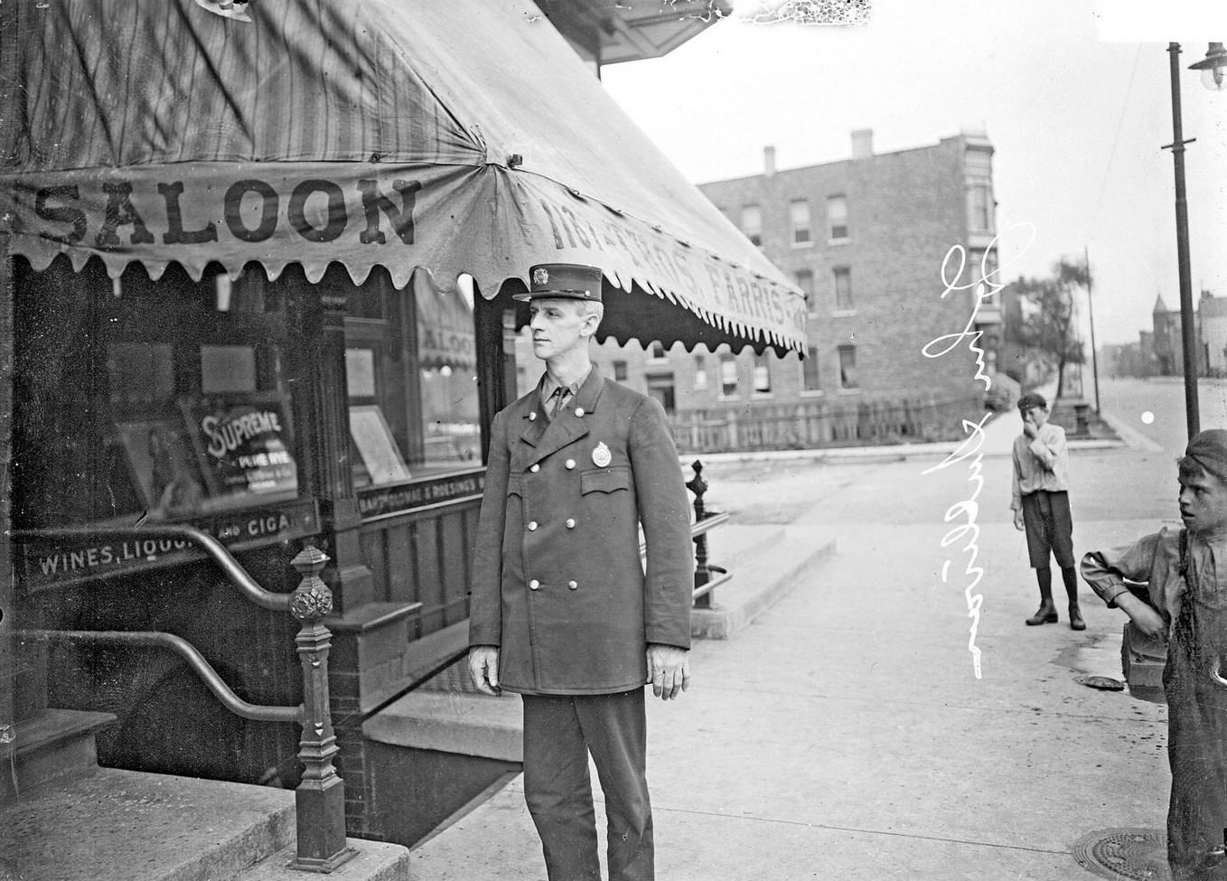 John Sullivan, a fireman, standing on a Chicago sidewalk, outside the Thomas Farris saloon, at 2200 West 13th Street in the Near West Side community area, 1910s.
