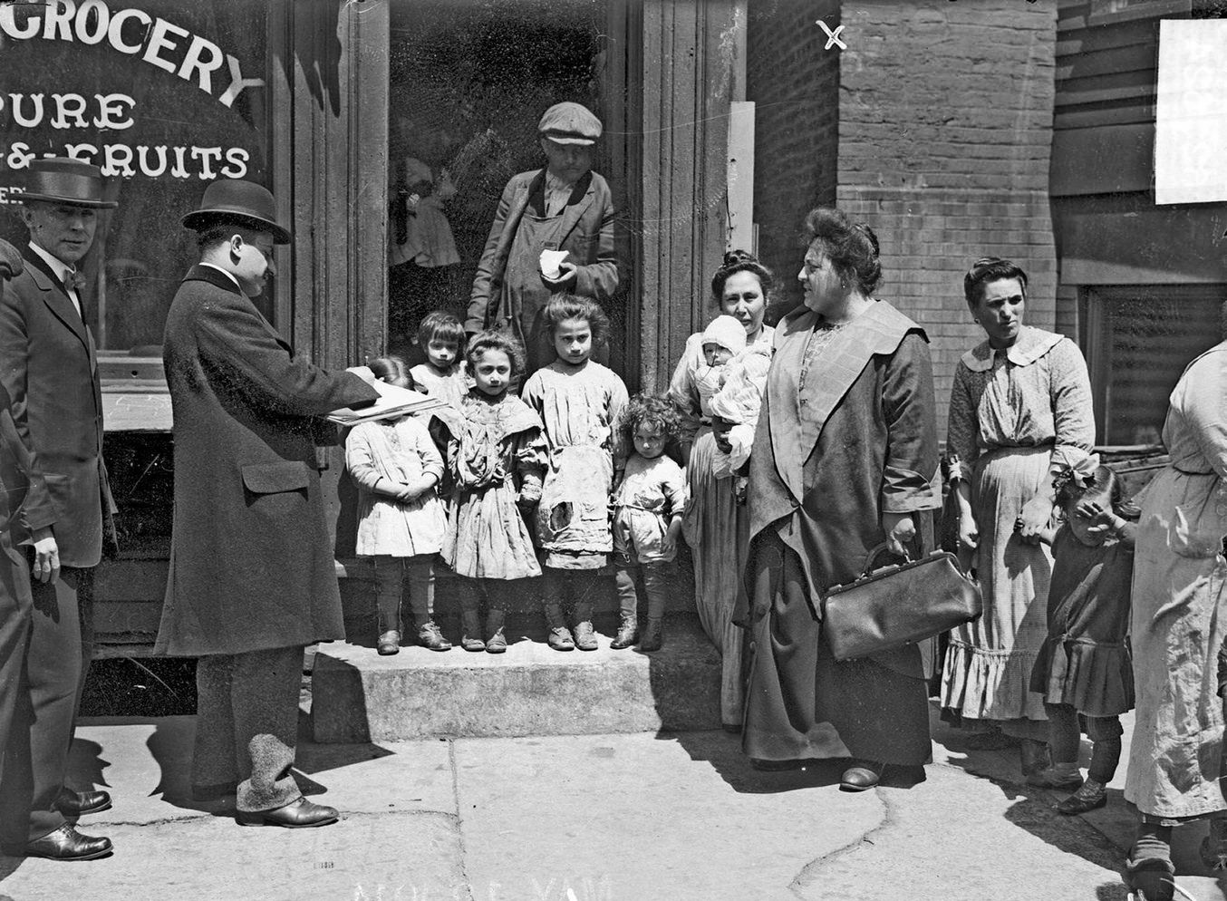 Annie Carlo-Blasi, queen of Little Italy, standing beside grocery store with men, women, and children, Chicago, Illinois, 1914.