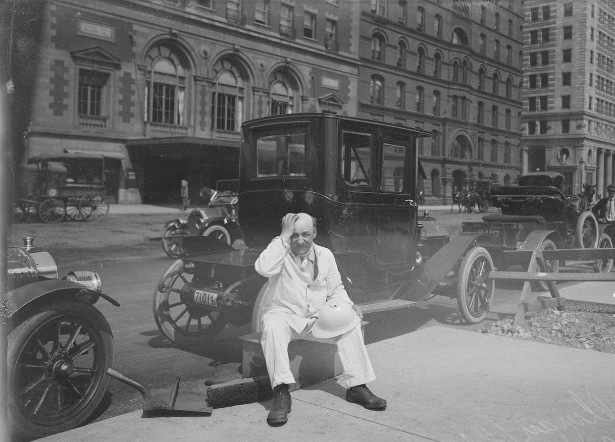 City of Chicago street sweeper on a hot day, sitting on a trash can on Michigan Avenue, across from Orchestra Hall, Chicago, Illinois, 1911.