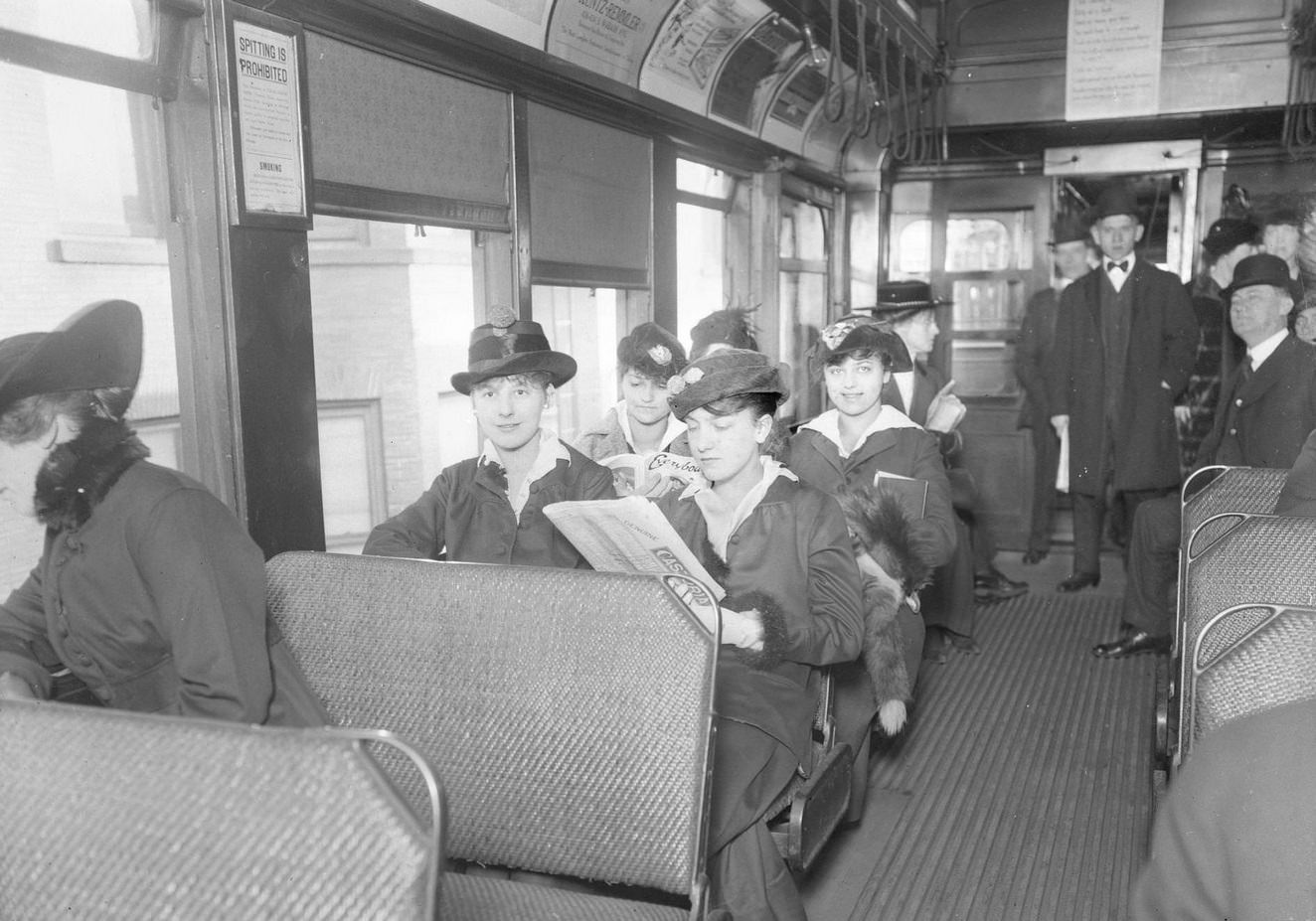 Passengers sitting on an open window elevated train car on the Jackson Park branch in Chicago, Illinois, 1910s.