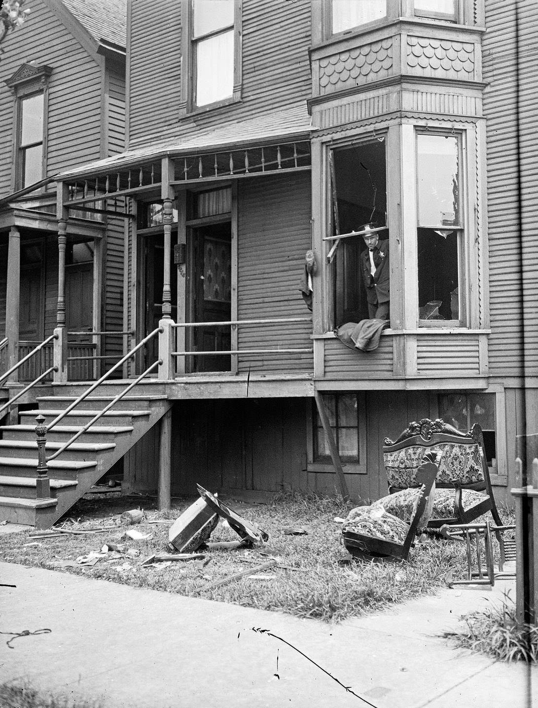 Police looking through a broken window of a house during the race riots in Chicago, Illinois, 1919.