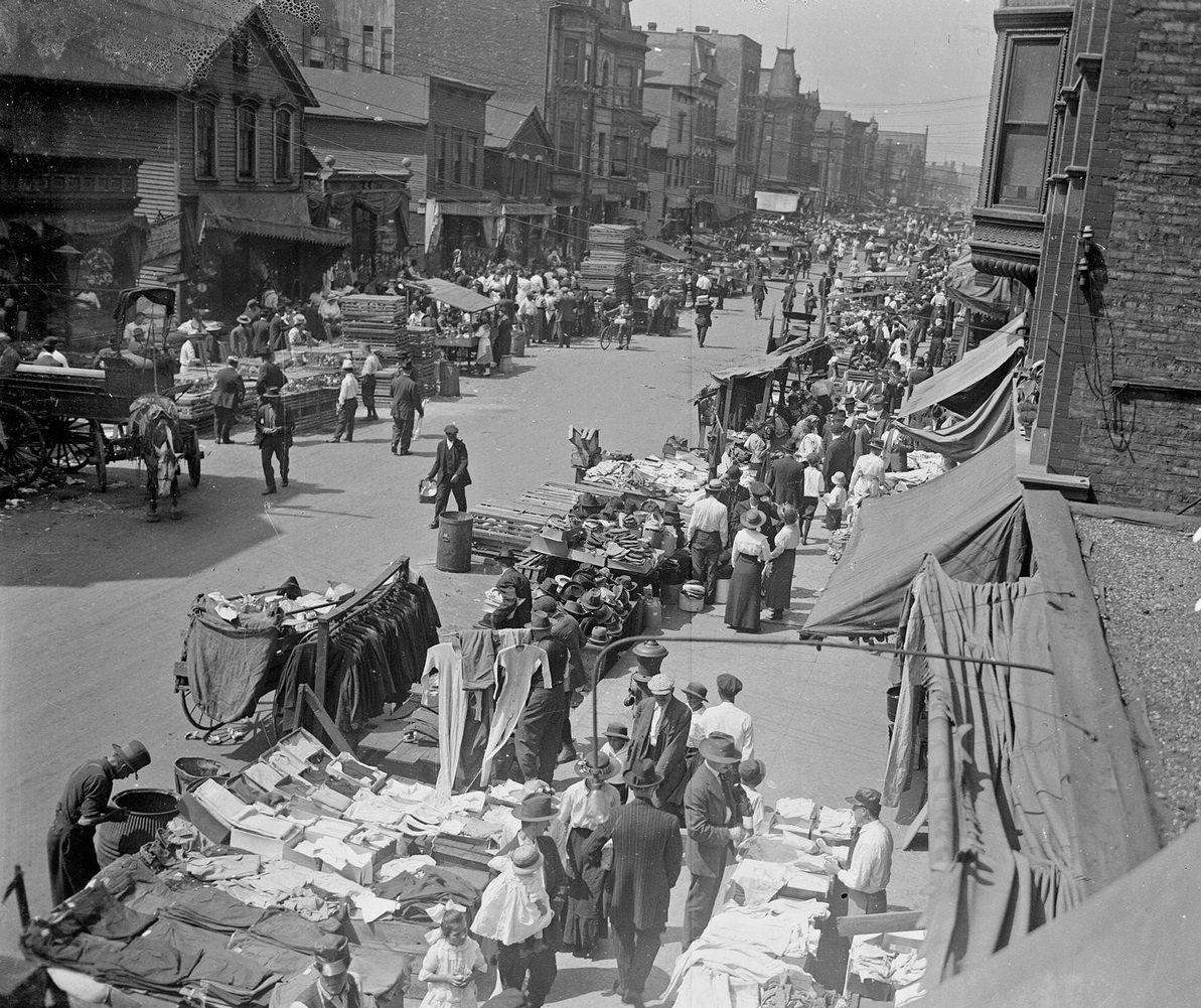 Clothing merchants selling goods along Maxwell Street, probably during the Sunday market, Chicago, Illinois, 1917.