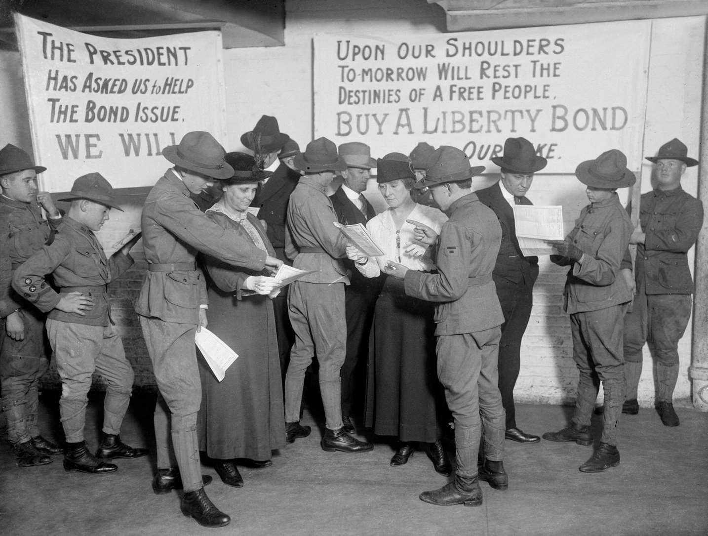 Boy scouts wearing U.S. Army uniforms sell Liberty Bonds to several men and women in a room in Chicago, Illinois, 1917.