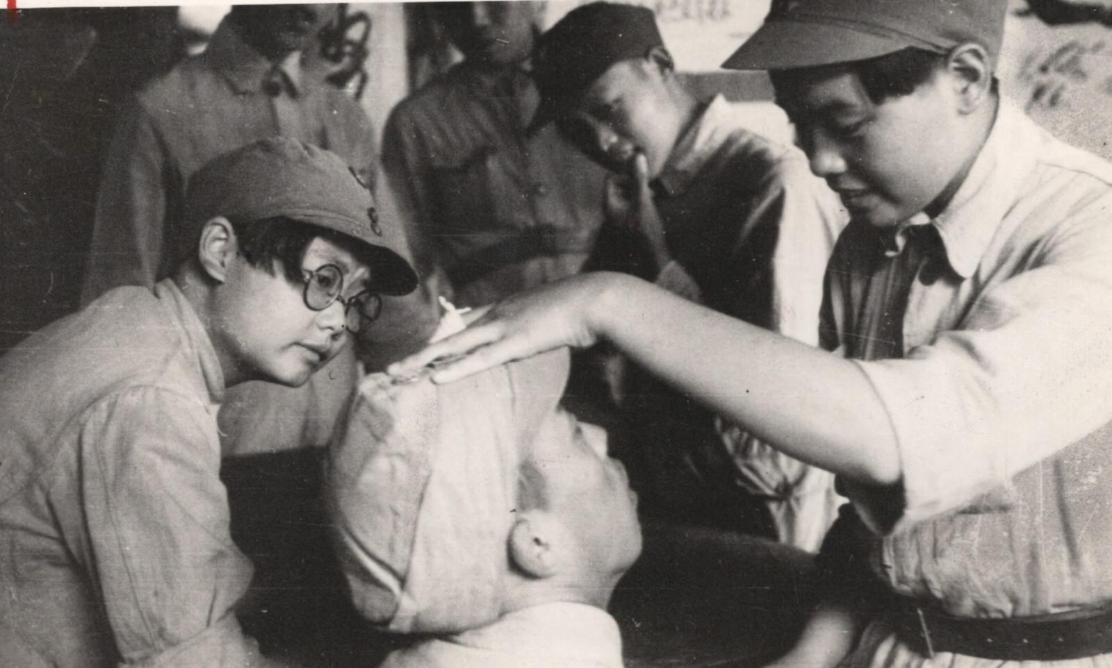 Qualified women nurse conducting a physical examination of guerrilla troops along the Tientsin-Nanking (Tianjin-Nanjing) railway in Anhwei (Anhui) Province. These young women were formerly nurses in Nanking (Nanjing).