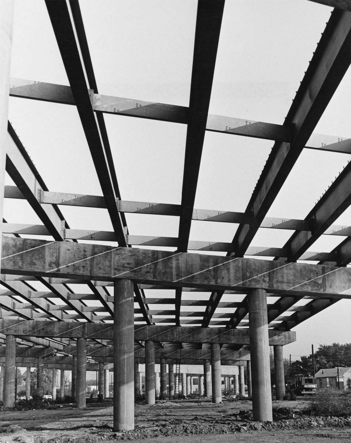 View up through the uncompleted steel framework of a bridge or road flyover, raised on reinforced concrete pillars, under construction in Dallas, Texas, 1955.