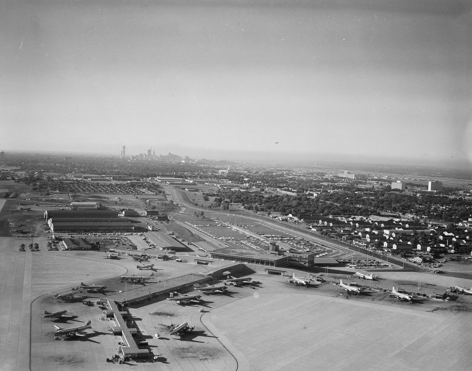 Dallas Love Field,1950. There are airplanes parked on the parking lot. There are a lot of buildings on the background.