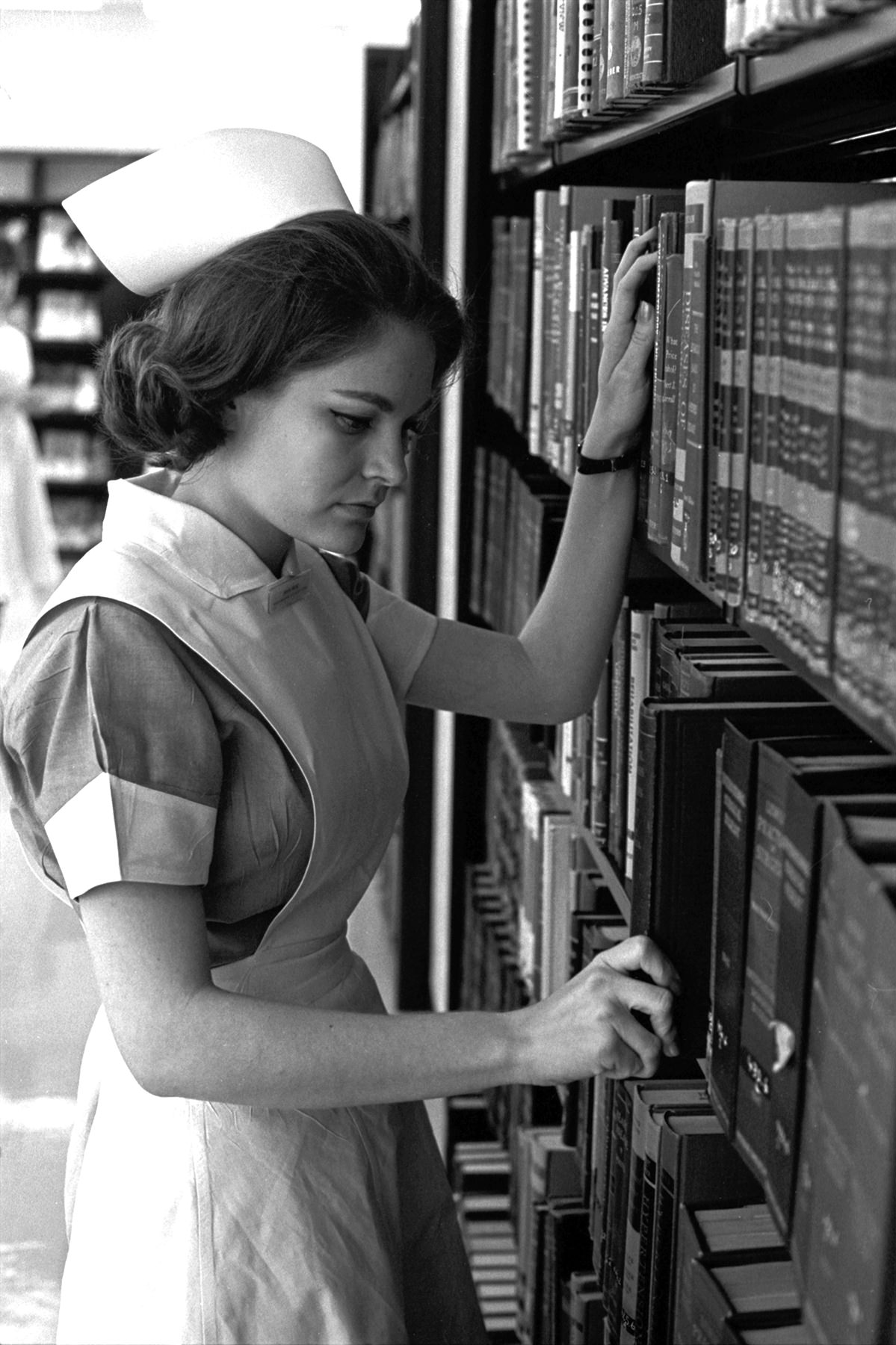 Miss Alita Rose, president of one of the two classes of student nurses at John Peter Smith Hospital School of Nursing, locates a book in the library and prepares to spend a couple of hours in quiet study, 1965