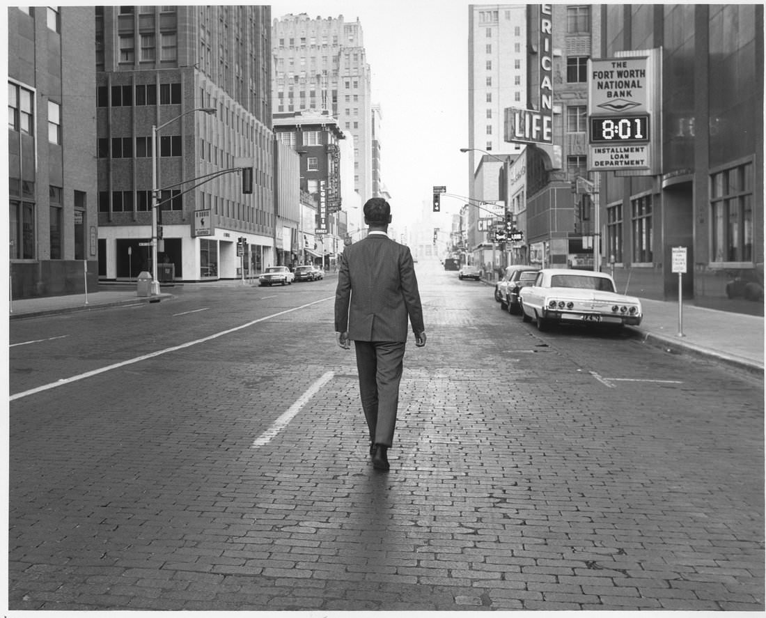 Main St. between 7th and 8th Streets showing Fort Worth National Bank sign and man walking down middle of street, 1960s