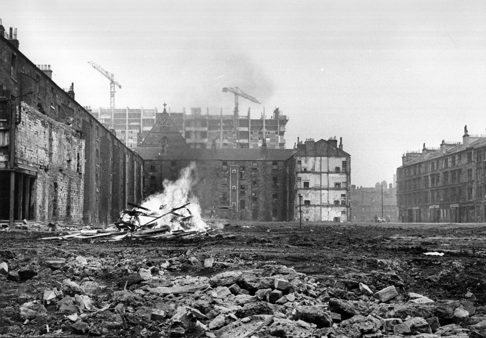 An area of cleared ground in the Gorbals area of Glasgow where debris from the newly-demolished slum tenements is being burnt on a bonfire, 1960