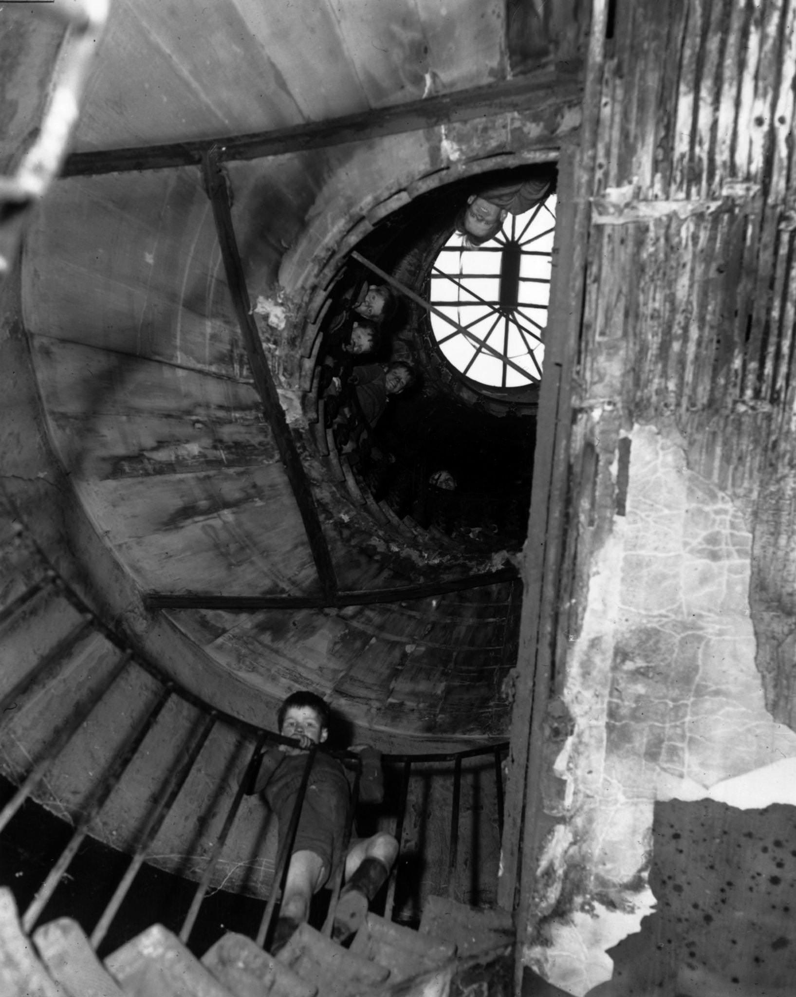 Children peer over the banisters of a spiral staircase in a tenement block in Nickelsar Street, the Gorbals, Glasgo, 1956.