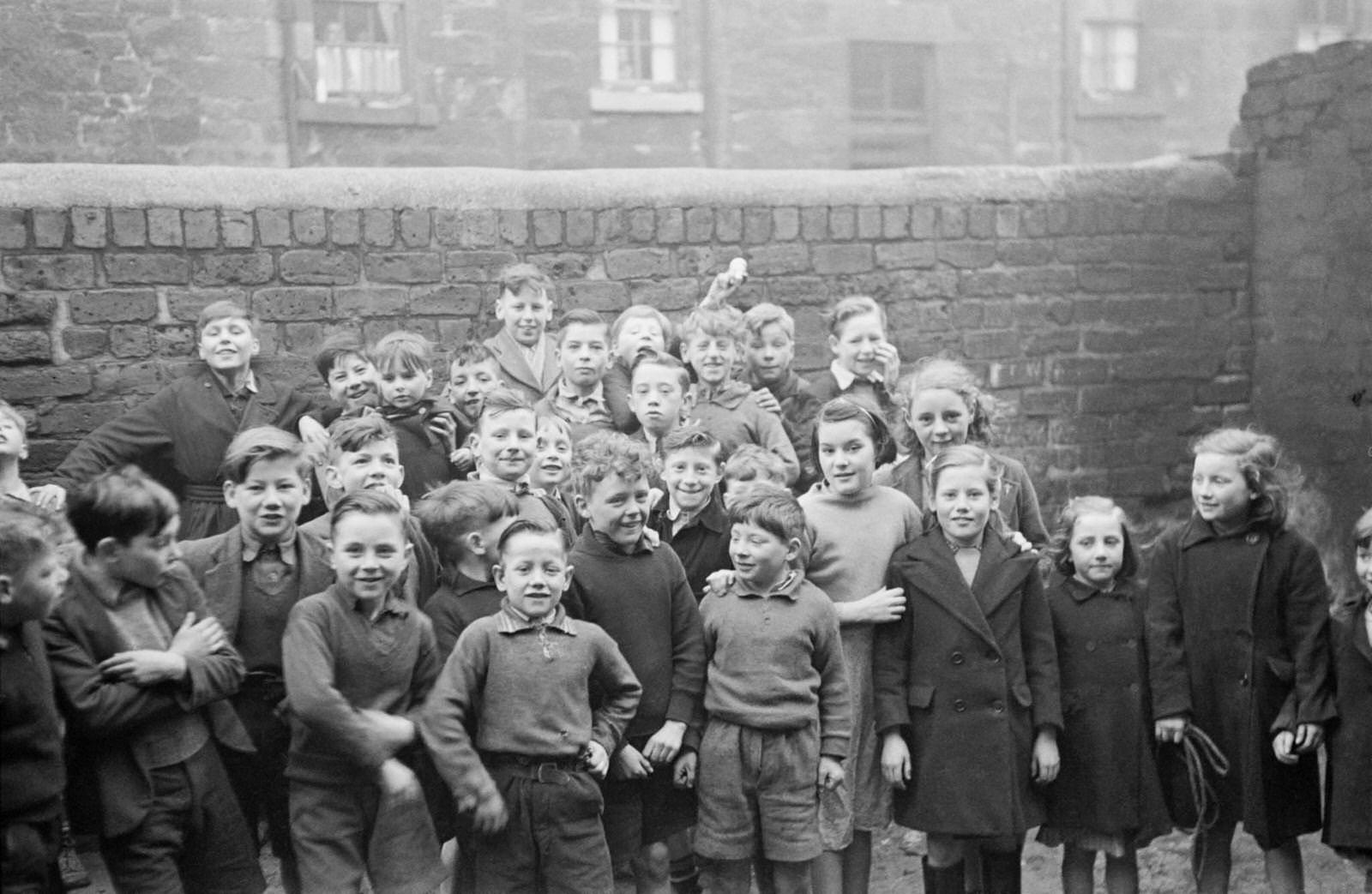 Boys and girls pose for the camera in the Gorbals, a slum district of Glasgow, 1948.