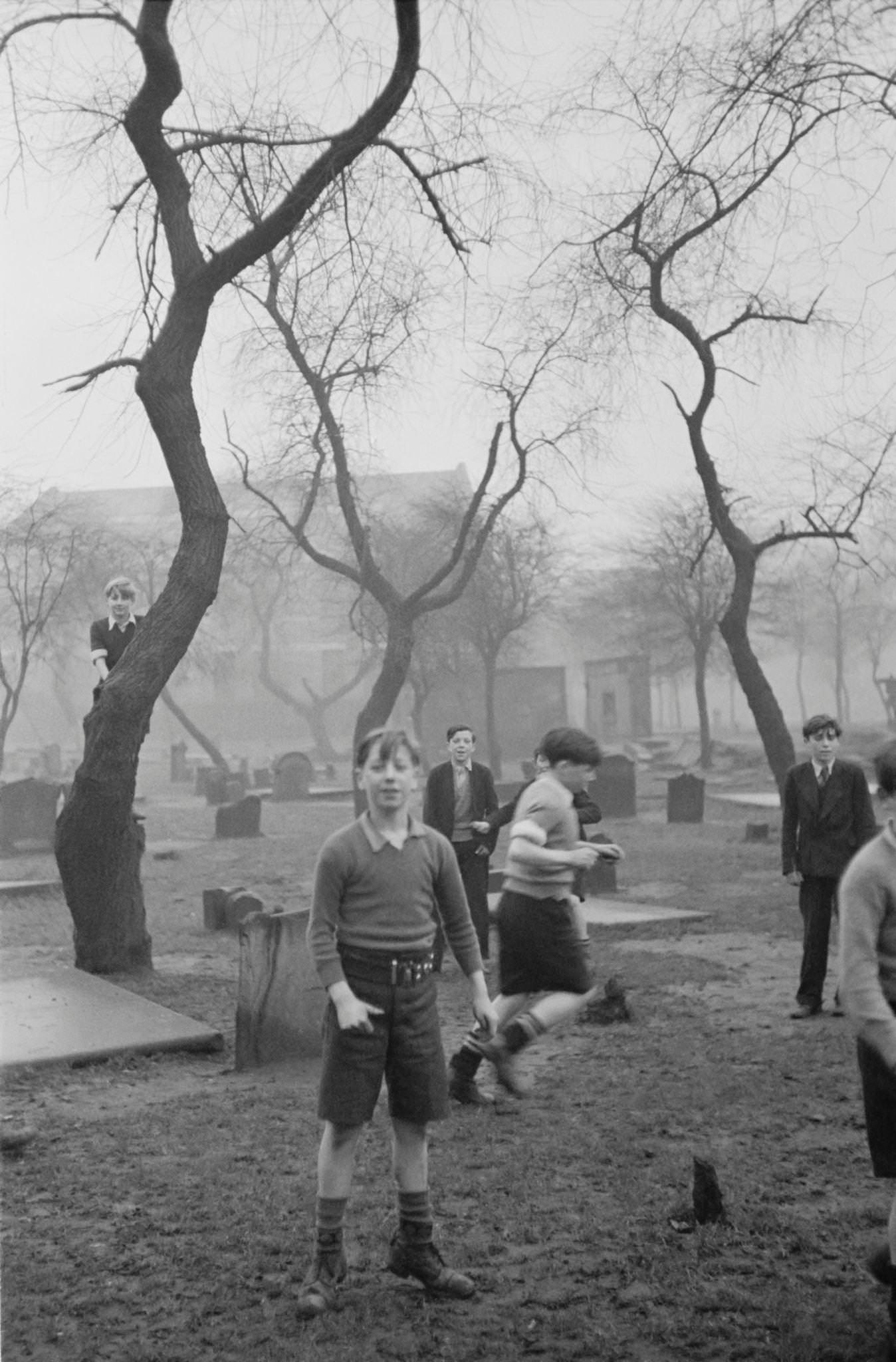 A group of boys play amongst the gravestones of the Corporation Burial Ground in Rutherglen Road, one of the few areas of greenery in the Gorbals, a slum district of Glasgow, 1948.