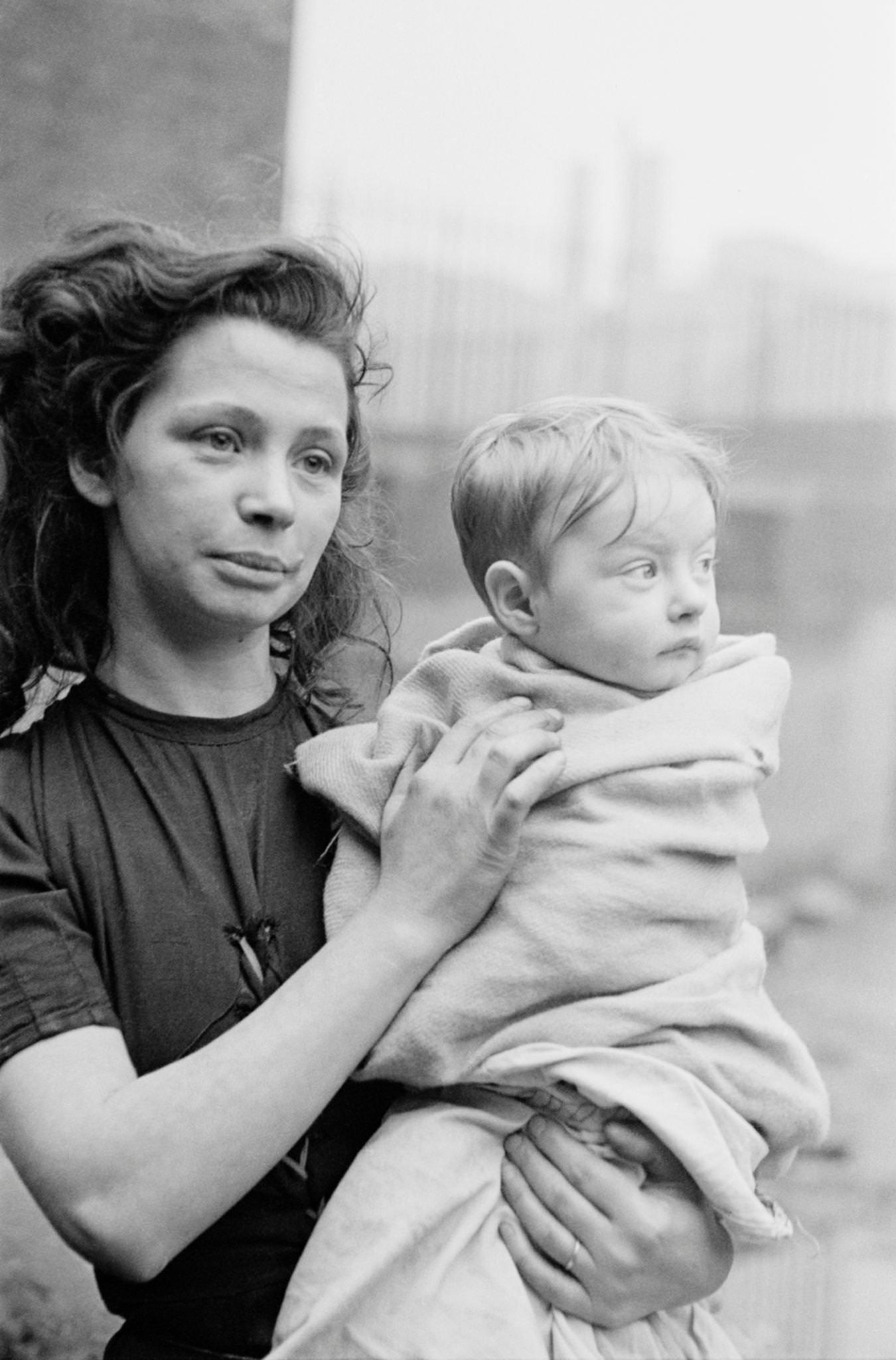 A young woman holding a baby wrapped in a blanket in the Gorbals, a slum district of Glasgow, 1948.