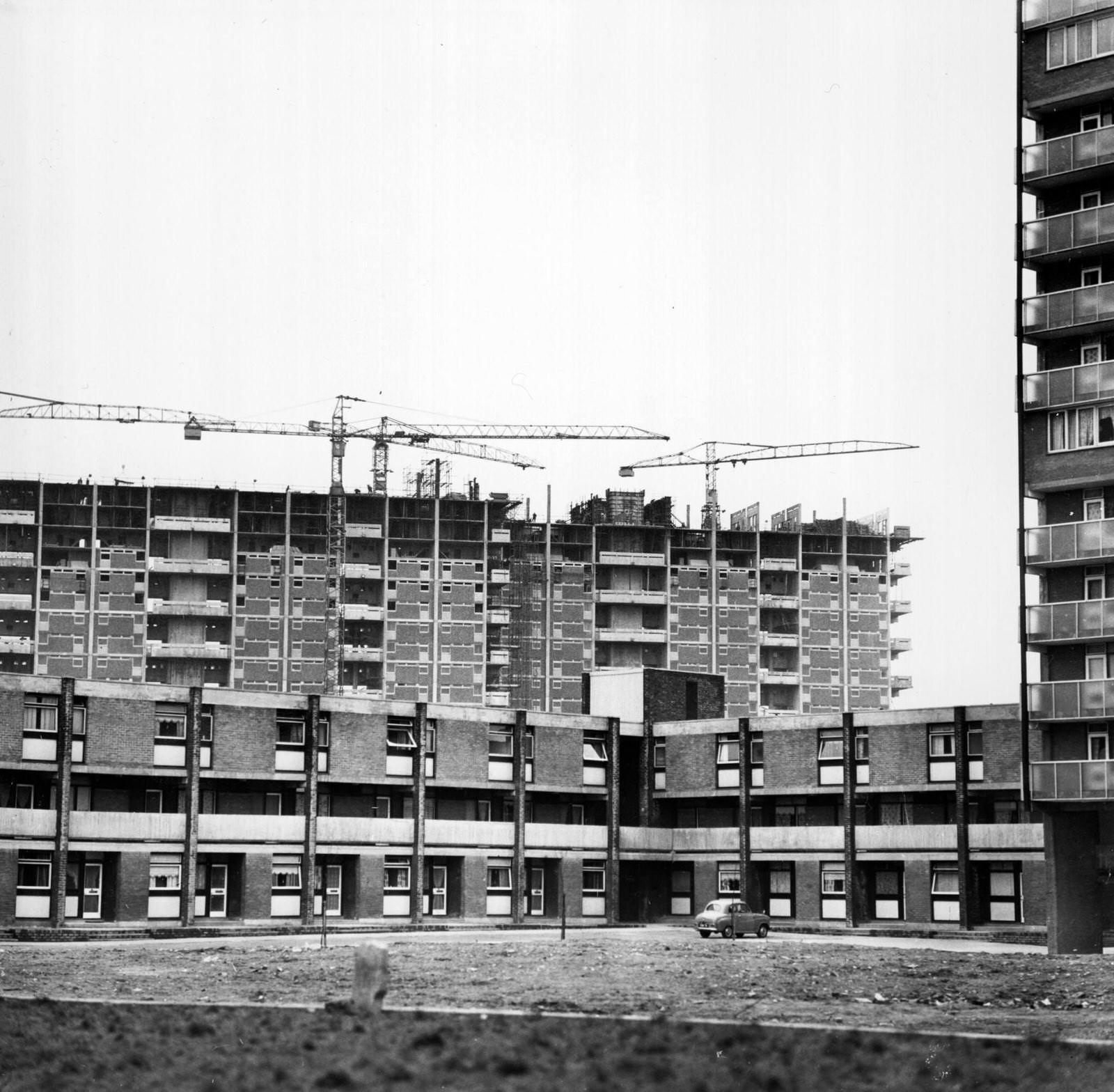 A woman and a little girl walking through an area of modern housing in the Gorbals area of Glasgow, 1960