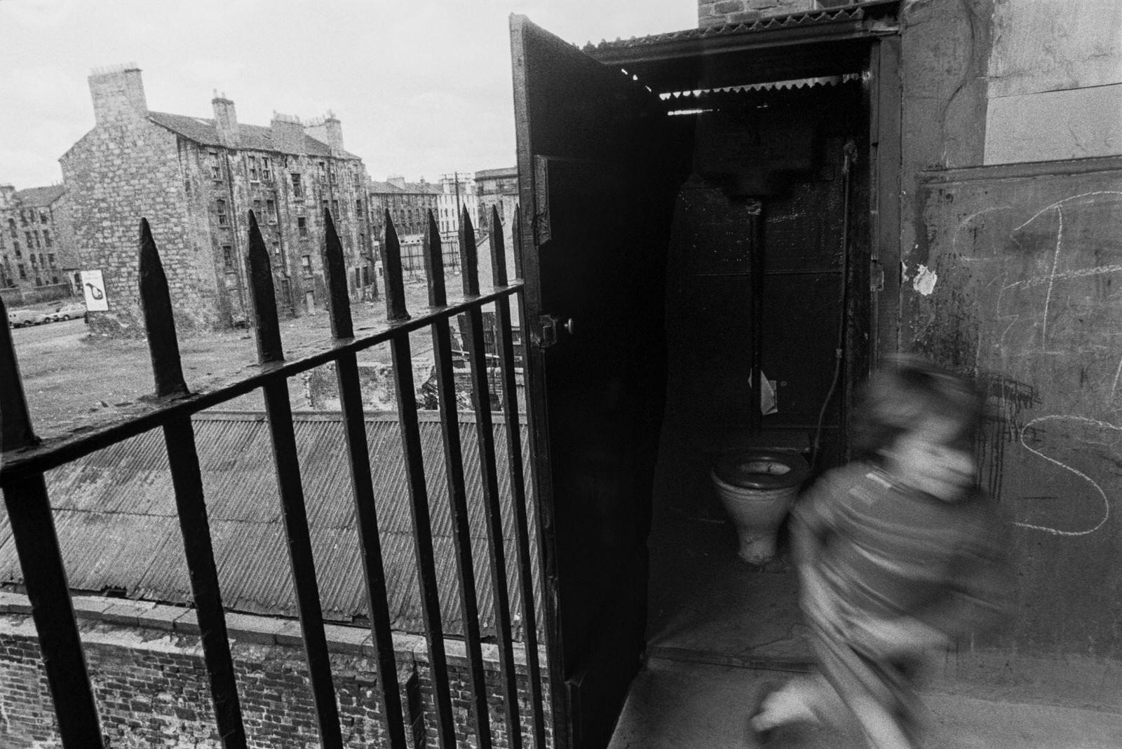 A little boy leaving an outdoor toilet in slum housing in the notorious Gorbals district of Glasgow in 1969.