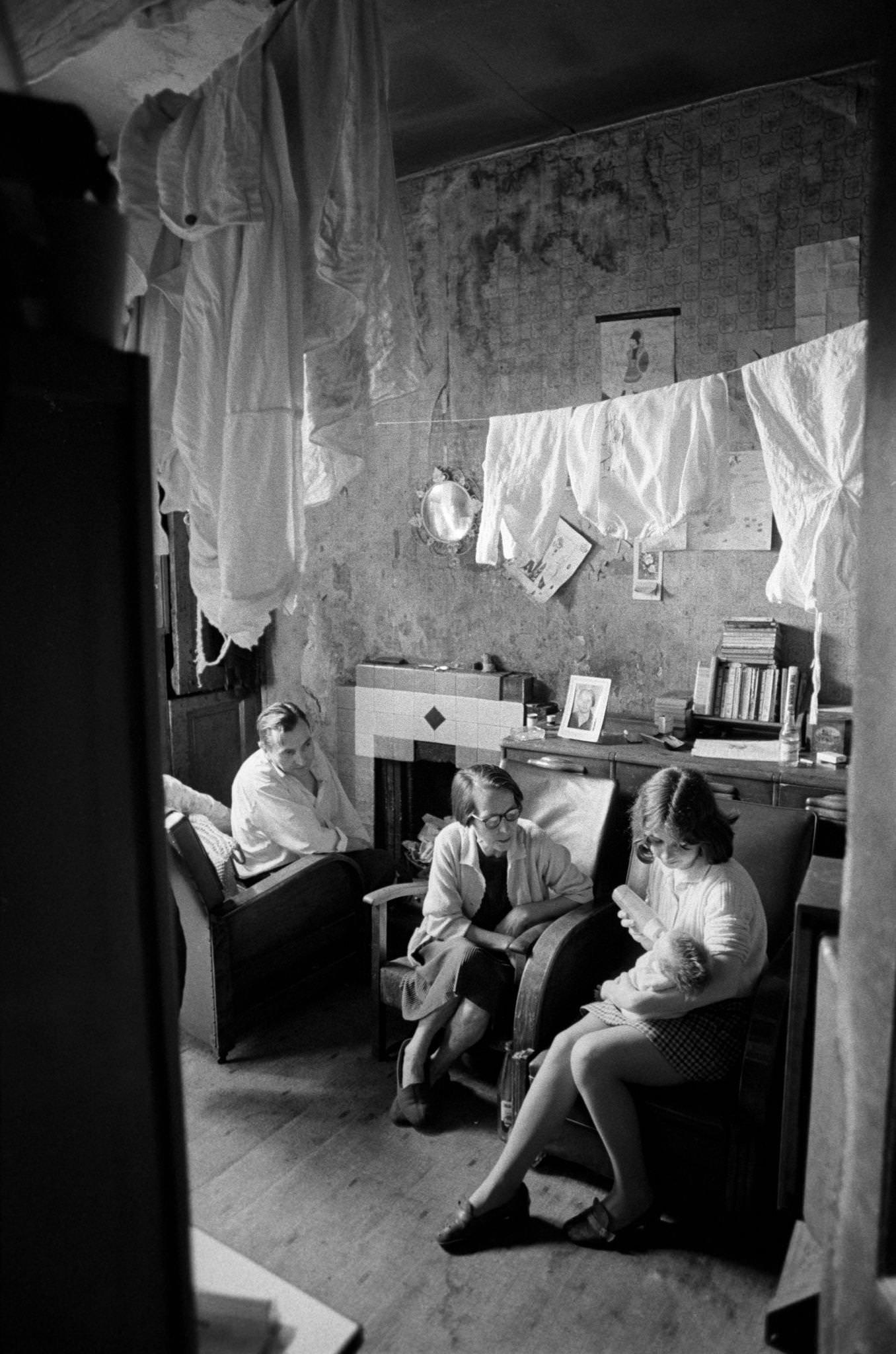 Four people, including an older couple and a young girl feeding her baby, in their home in the notorious Gorbals district of Glasgow, 1969.