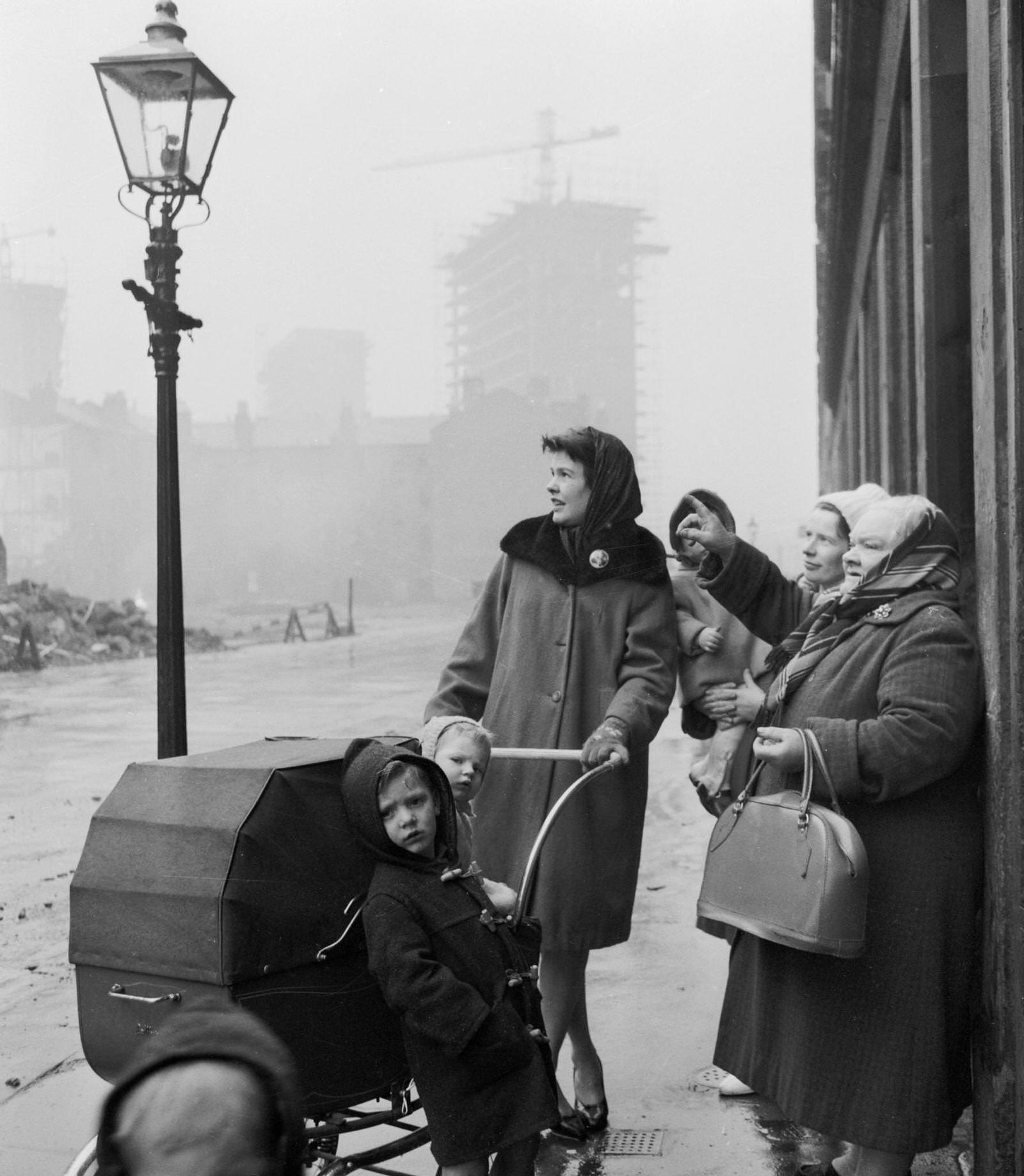 A group of women and children stop to look at across the street where sections of the notoriously squalid slums known as the Gorbals have been demolished, 1962