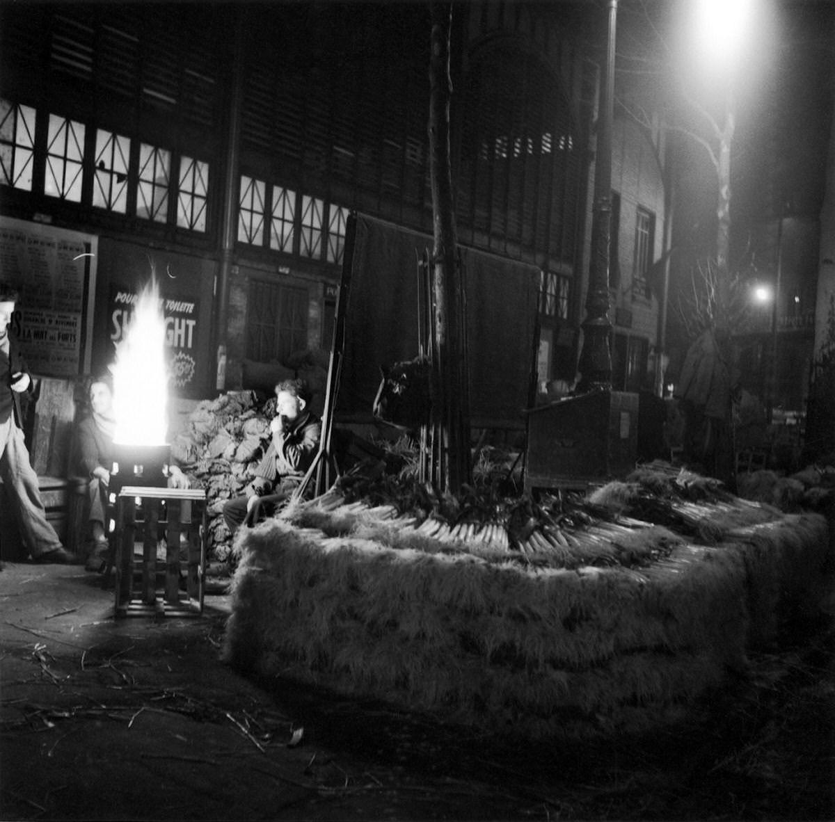 Men in front of a brazier behind leeks at night in Les Halles, 1953
