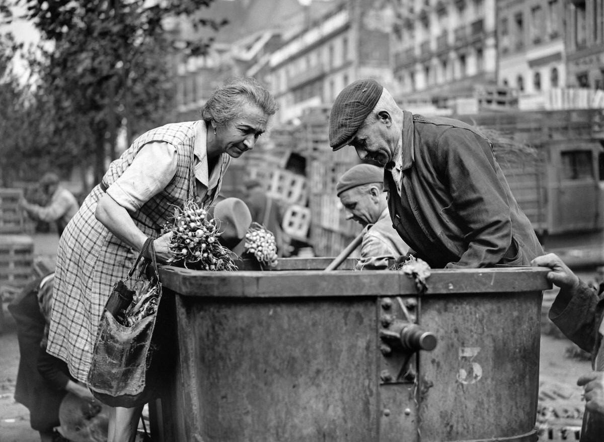 People search a garbage can in August 1946, in the district of Les Halles in Paris, at the resumption of the activity in the Halles quarter