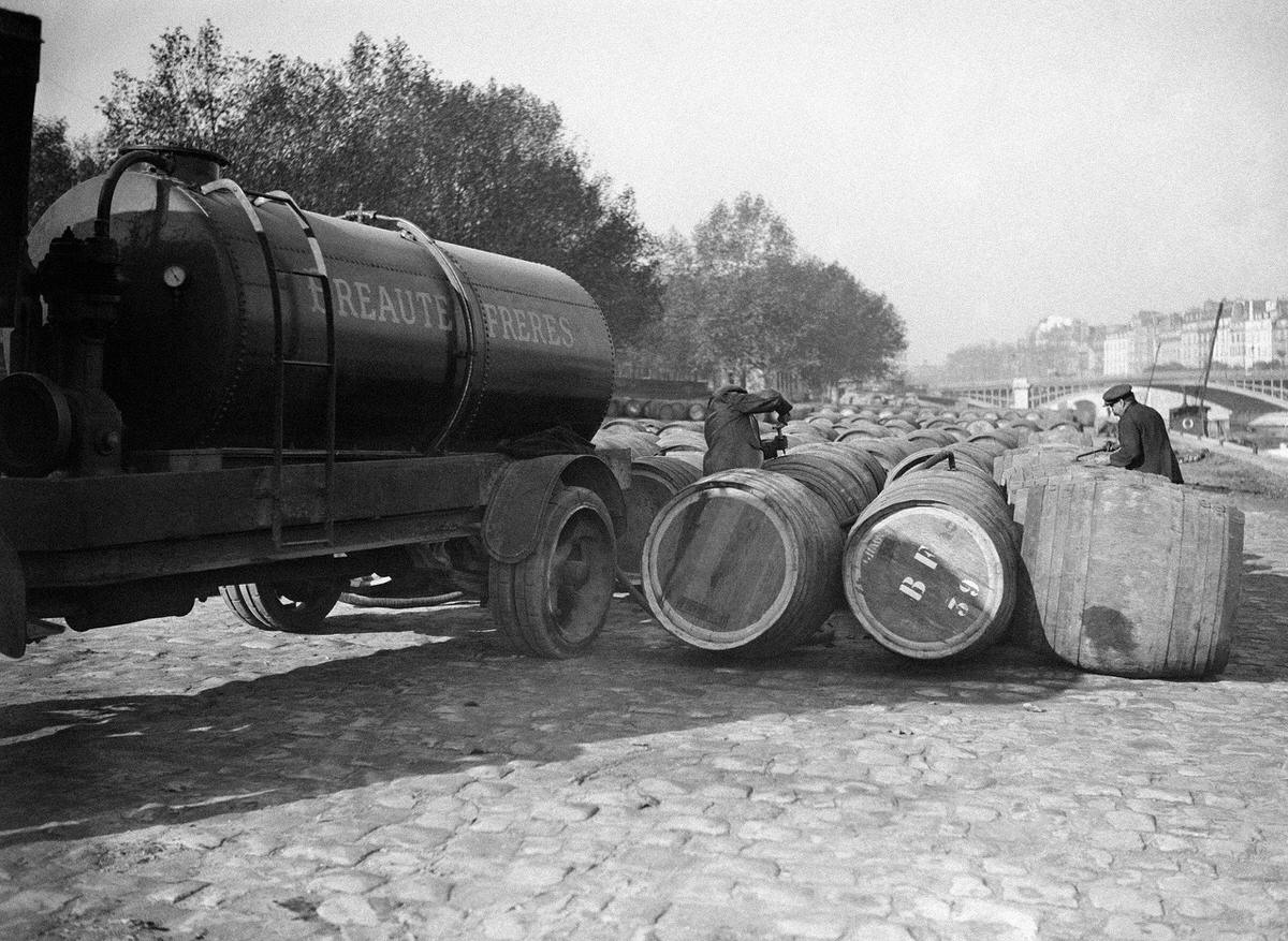 Workers filling barrels with wine, on the quay, near Les Halles au vin, in Paris, France on November 6, 1931.