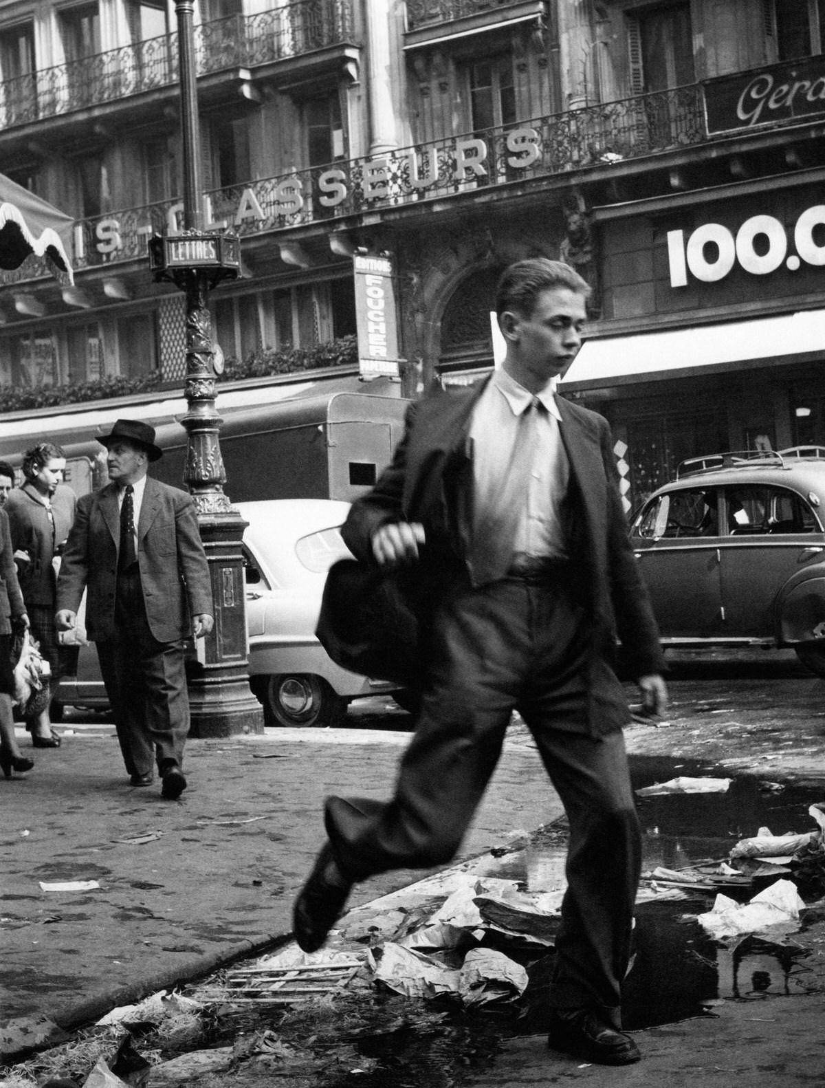 A man jumping over a gutter in les Halles, 1953