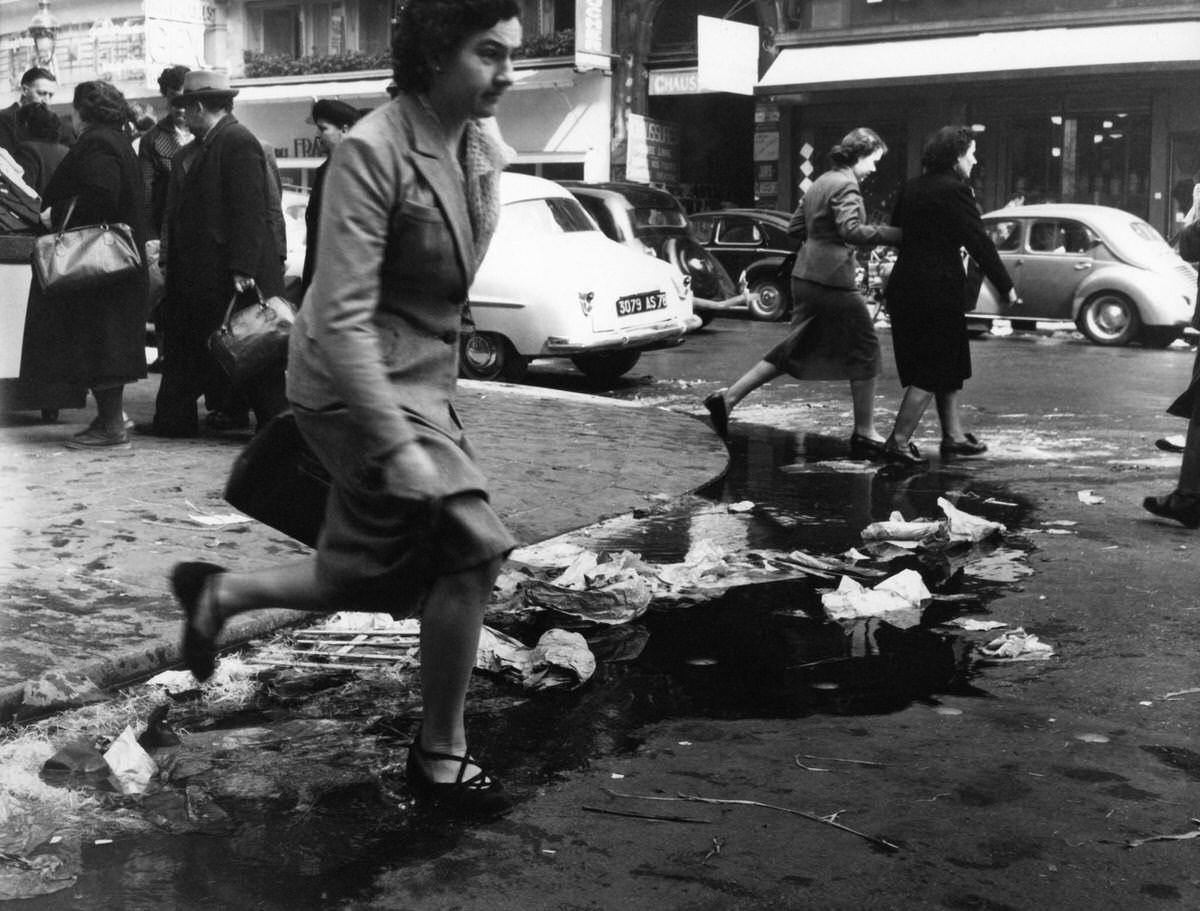 A woman jumping over a gutter in les Halles, 1953