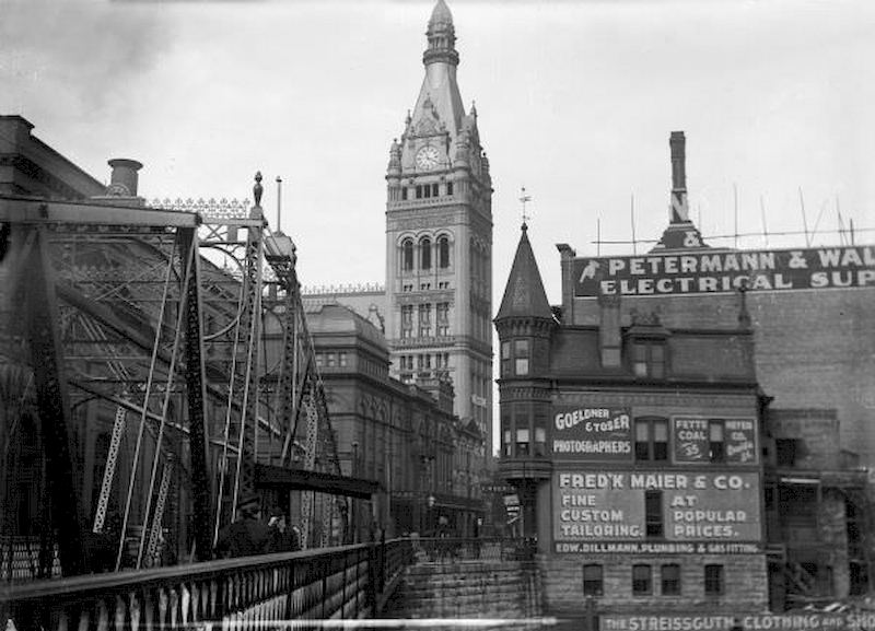 A bridge crosses the Milwaukee River on Oneida Street, now known as Wells Street, looking toward the City Hall tower, 1895
