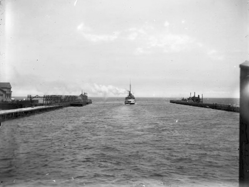 A boat leaving Milwaukee Harbor between two breakwaters, steaming into Milwaukee Bay and onward out into Lake Michigan, 1899