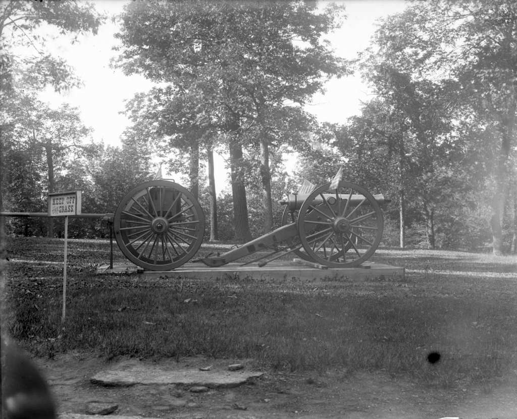 A cannon at Soldiers Home adorned with American flags near a sign reading 'Keep off the grass,' Milwaukee, Wisconsin, July 30, 1898.