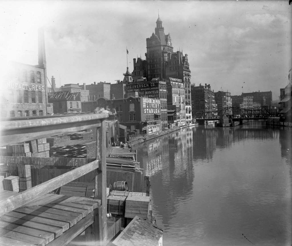 Pier or dock of buildings along the Milwaukee River, including a building with a clock tower, Milwaukee, Wisconsin, 1898.