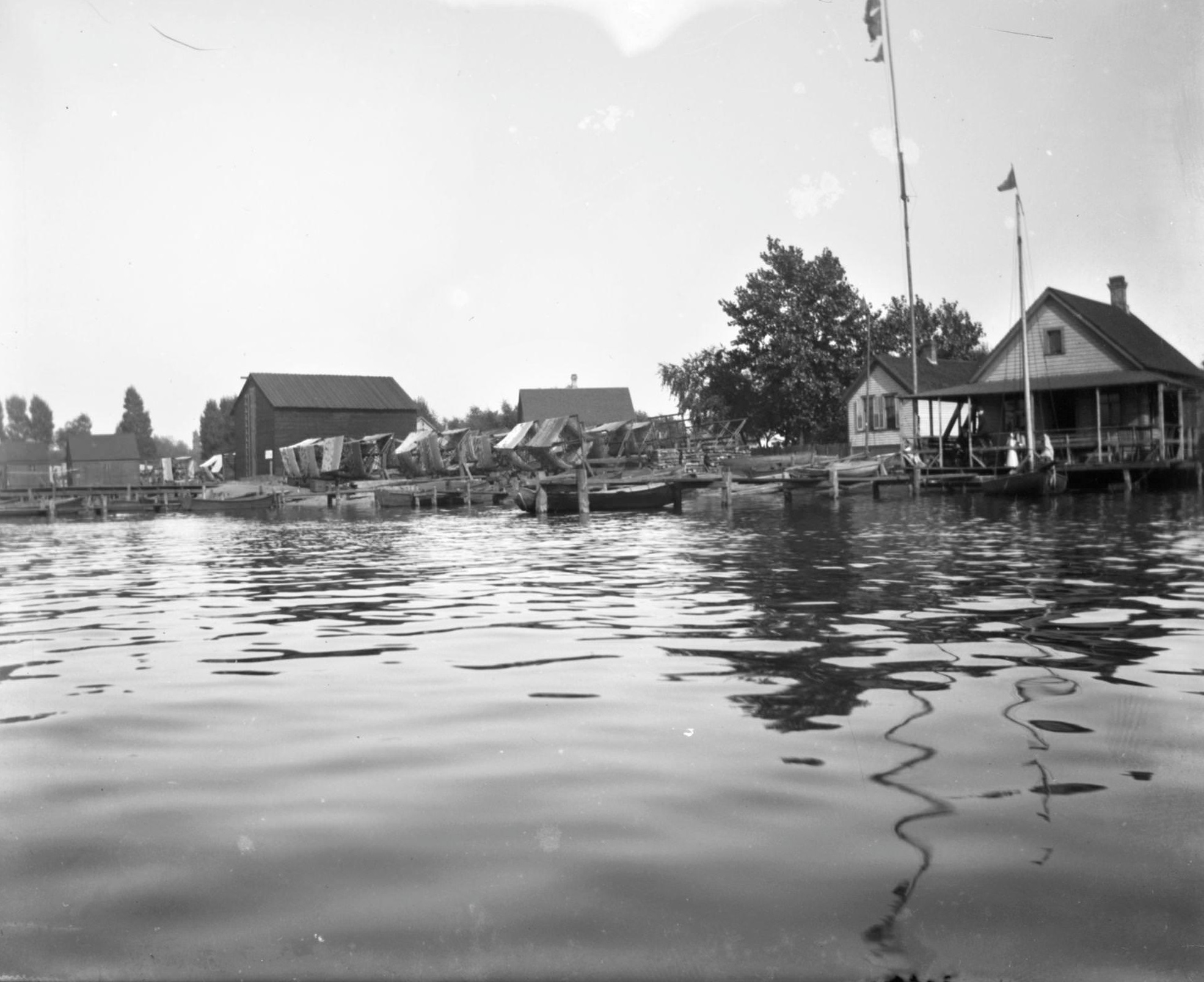 View from water of boats docked near houses on Jones Island, Milwaukee, Wisconsin, 1898.