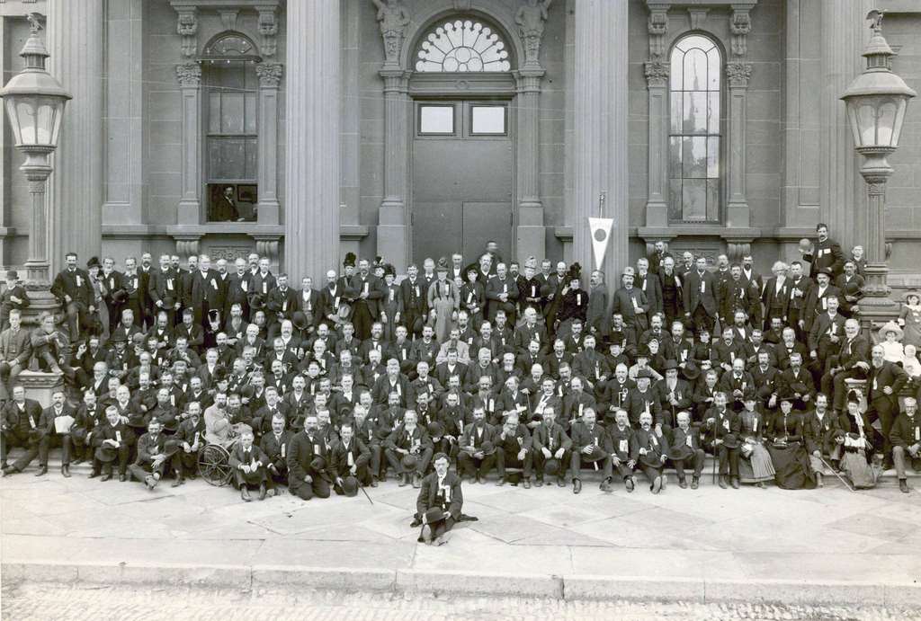 A group of Civil War veterans and their families pose in front of the Milwaukee armory building at the reunion of The Iron Brigade, Milwaukee, Wisconsin, September 1887.