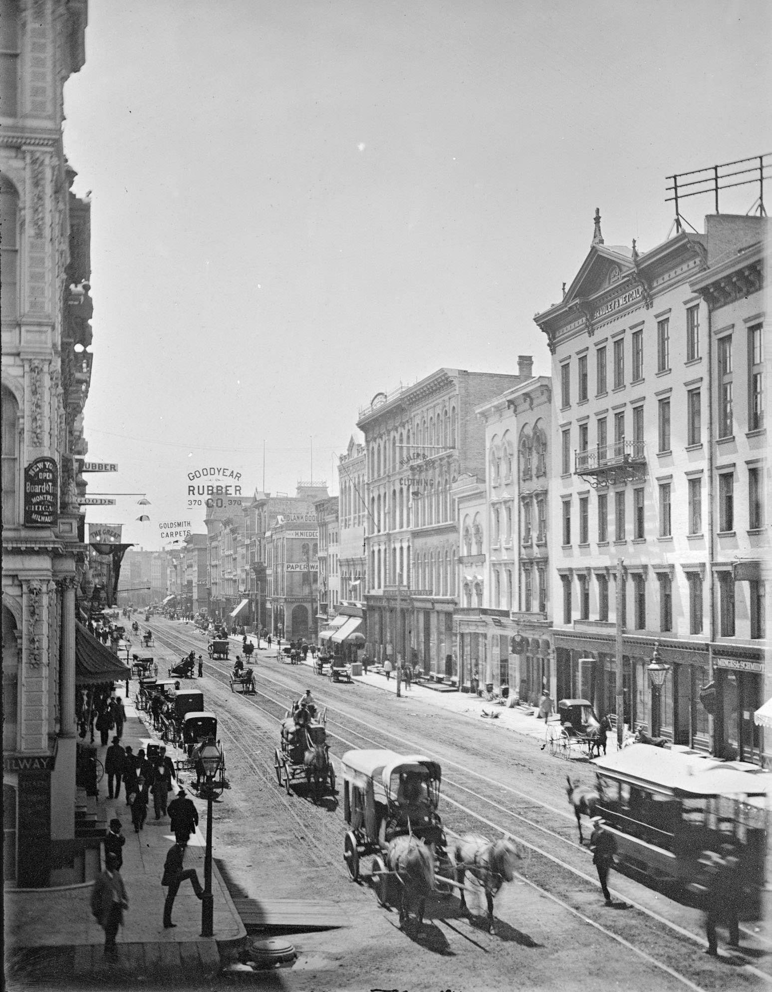 Elevated view down East Water Street from Wisconsin Avenue, with buildings, people, and street traffic including horse-drawn vehicles and a horse-drawn streetcar, Milwaukee, Wisconsin, 1885.