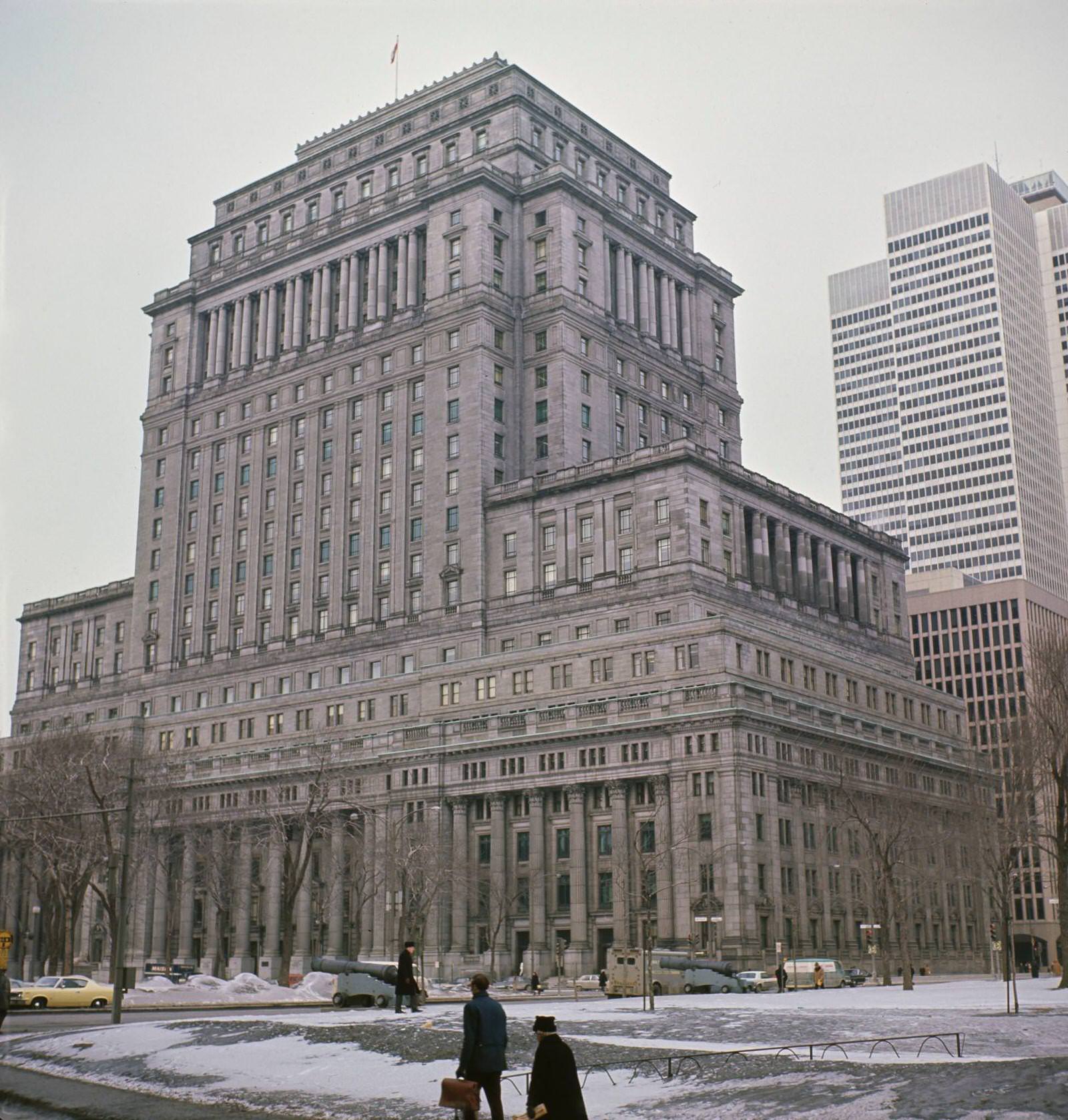 Pedestrians cross a snow covered Dominion Square (now Dorchester Square) in front of the Sun Life Building on the corner of Rene Levesque Boulevard West in the downtown centre of the city of Montreal, 1965