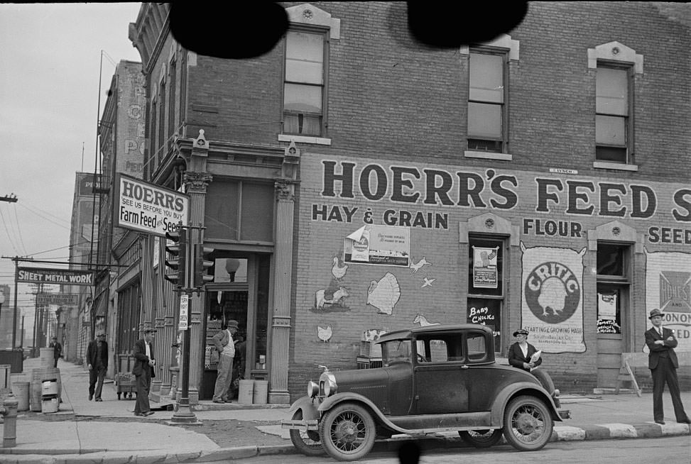 Waiting for a bus in front of feed store, Peoria, Illinois, 1938