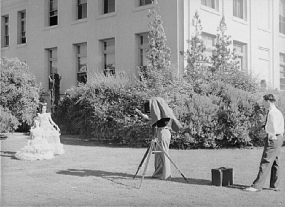 Photographer instructs high school girl in graduation play costume how to pose, Phoenix, Arizona, 1940