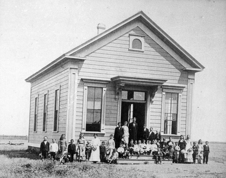 View of the first school in Williams, California with school children posing outside, 1880