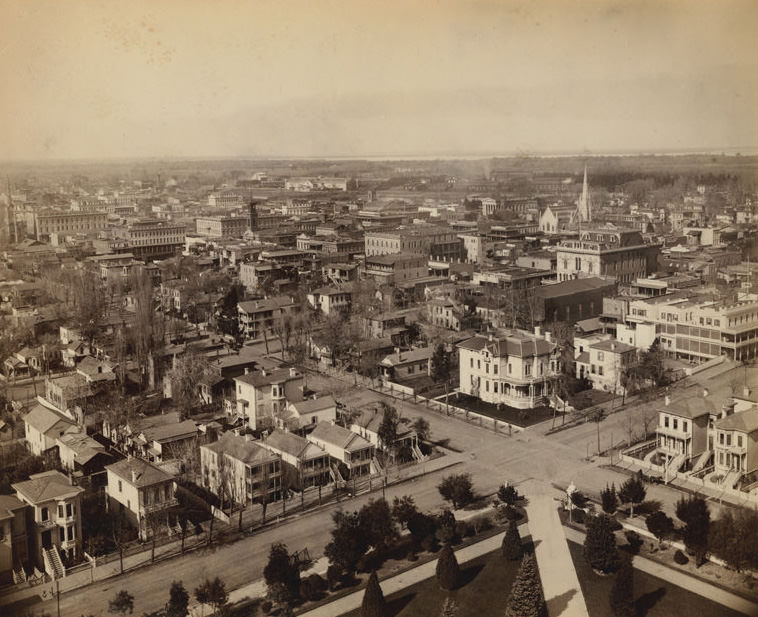 Elevated view of the city looking north west from the State Capitol. Shows residents, churches, businesses, 1880