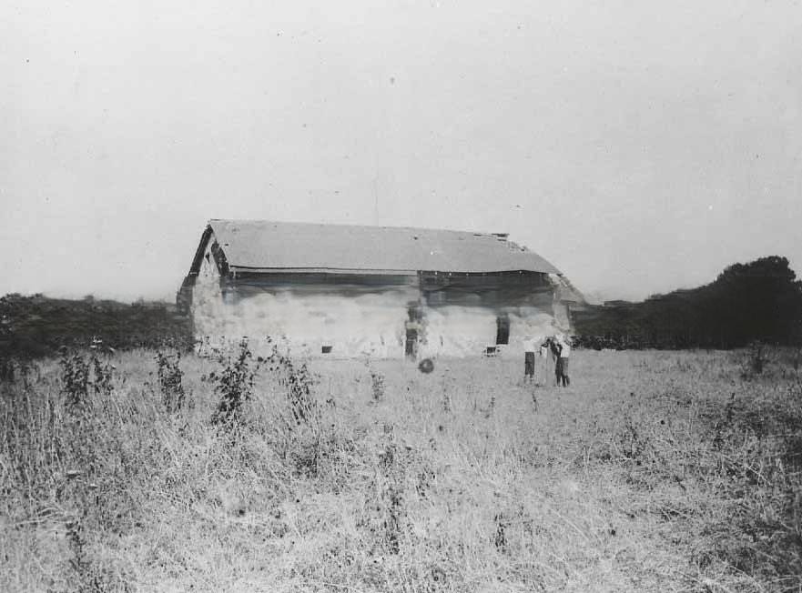 Sutter's Fort central building before rebuilding. View with a man and two boys standing next to the building, 1889