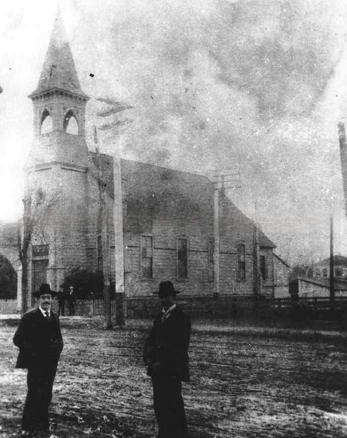 An unidentified church and two men standing in the street in front of the church, 1880