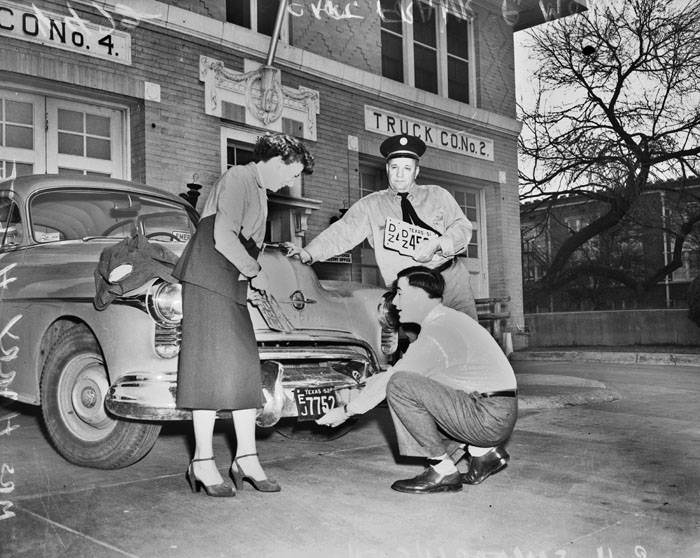 Frank Monaco watching as license plates are removed from car, 1953