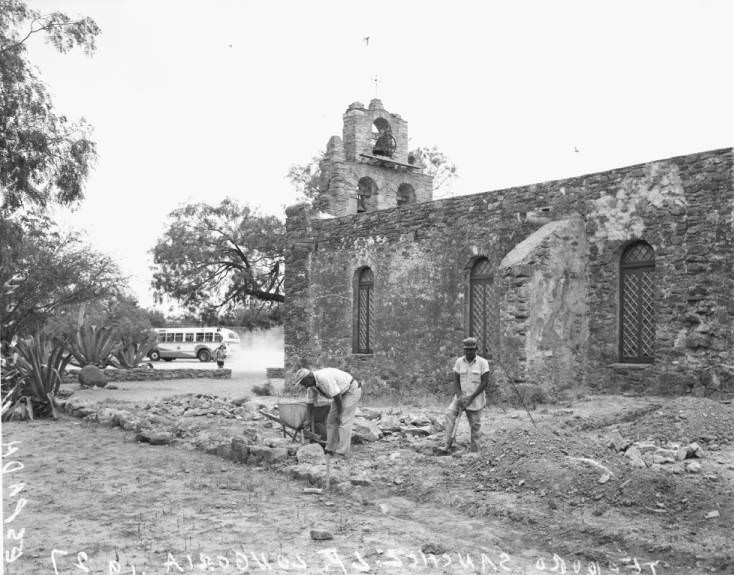 Teodoro Sanchez and L.P. Longoria working outside the church at Mission Espada, 1956