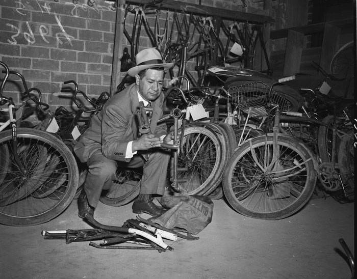 Police Detective Sixto Sepulveda with stolen bicycle parts stored in police headquarters basement, 1950