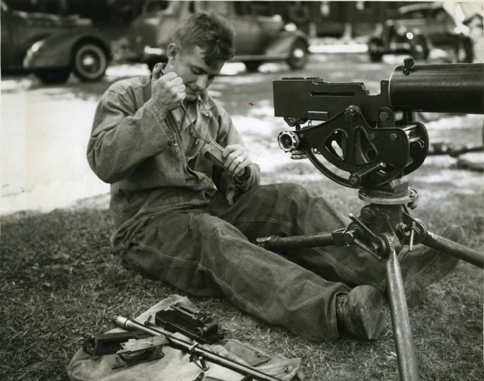 Private Bredemeyer thought he would take this machine gun apart to see what made it "tick." An apparent case of "spring fever" is handicapping his efforts to get it back together again, 1937