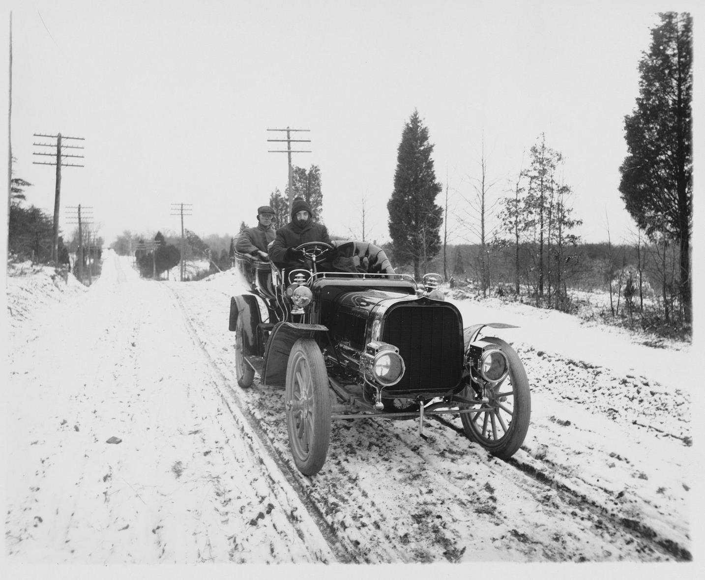 A man drives a passenger through the snow in a Pope-Toledo automobile in 1905