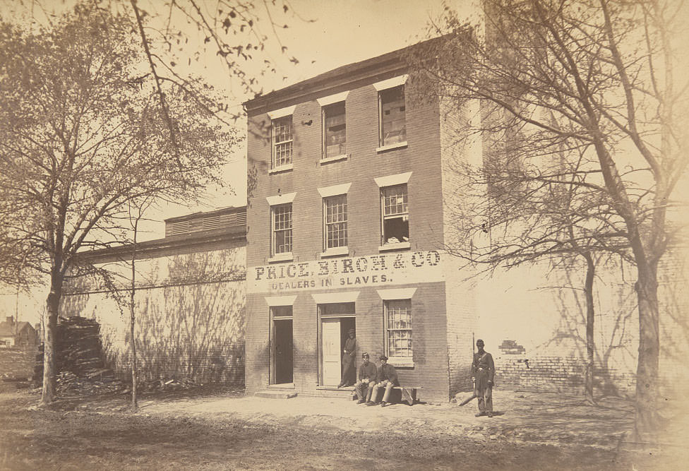 A Union army guard and other men in front of a building designated Price, Birch & Co., dealers in slaves, at 1315 Duke St., Alexandria, 1865