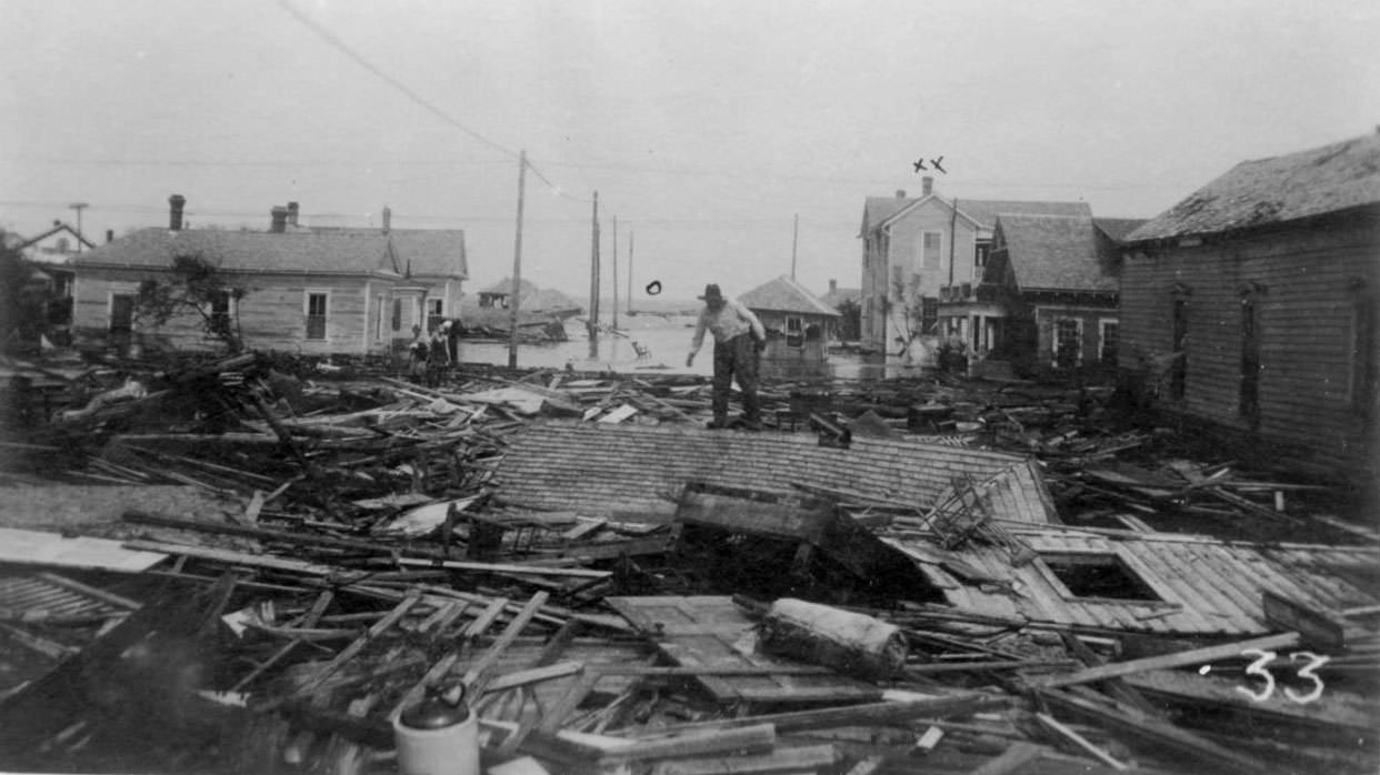 A man standing on a roof that lies on the ground after the hurricane of 1919 in Corpus Christi.