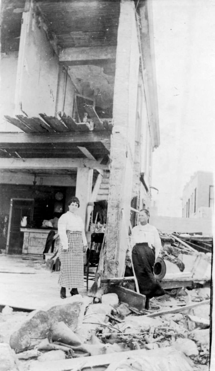 Two women standing beside the damaged building at the Seaside Hotel after the 1919 hurricane in Corpus Christi.